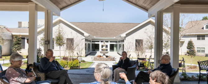 a group of older adults socializing outside at a senior living community
