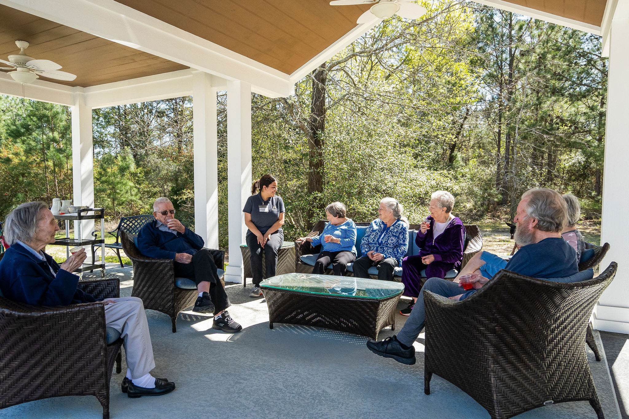 Assisted living residents and staff members laughing at Sundale Senior Living's outdoor veranda