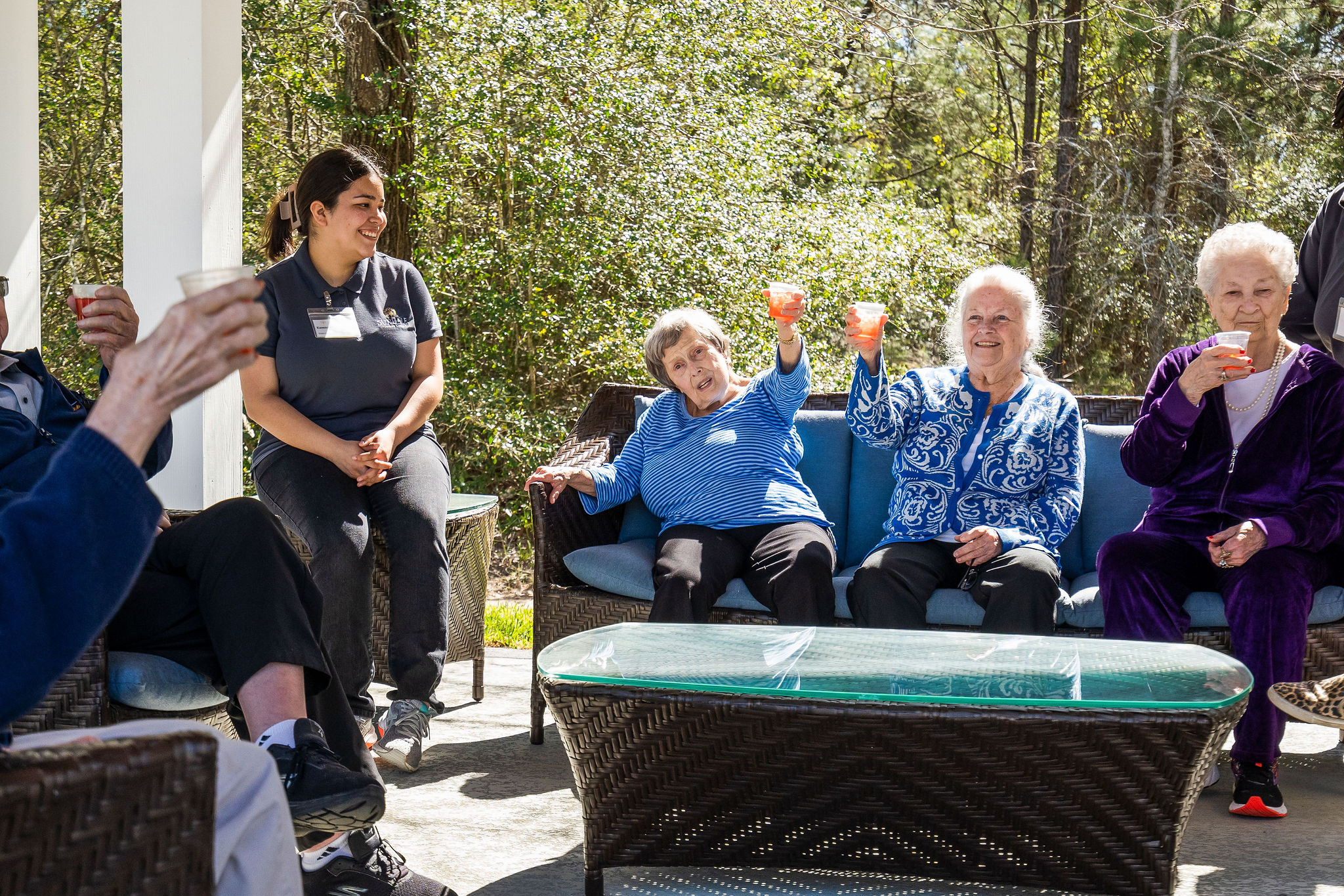 Residents of Sundale Senior Living in Huntsville, TX, "cheersing" each other with lemonade beneath the outdoor veranda