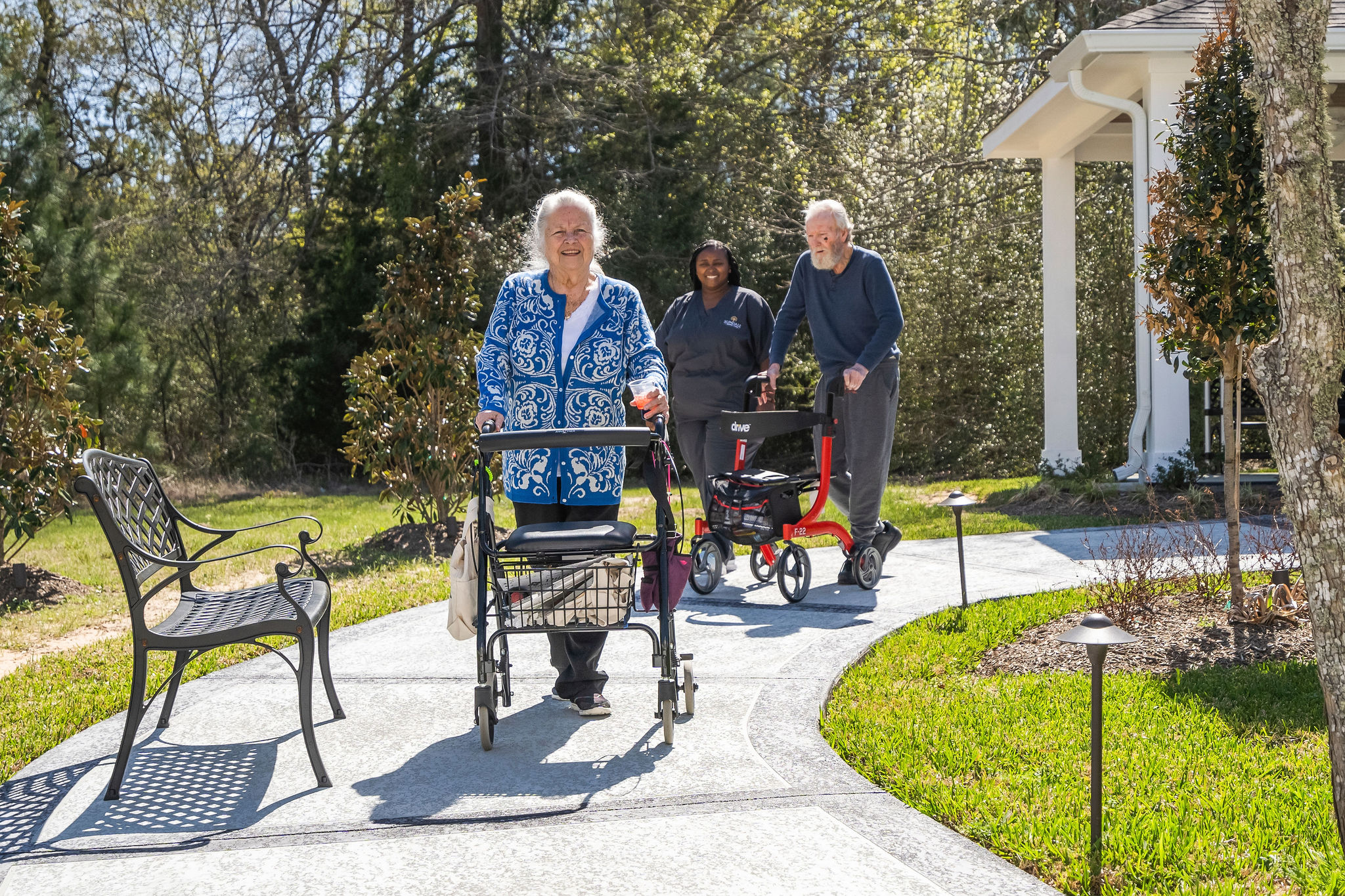 Two assisted living residents take a walk back inside at Sundale Senior Living in Huntsville, TX, with a staff member close behind
