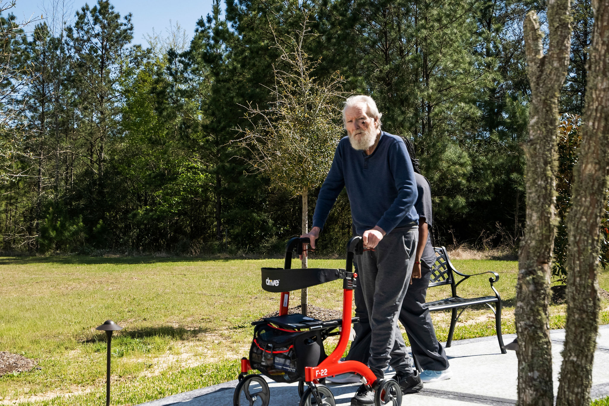 A resident and staff member taking a walk on the well-maintained grounds of Sundale Senior Living in Huntsville, TX