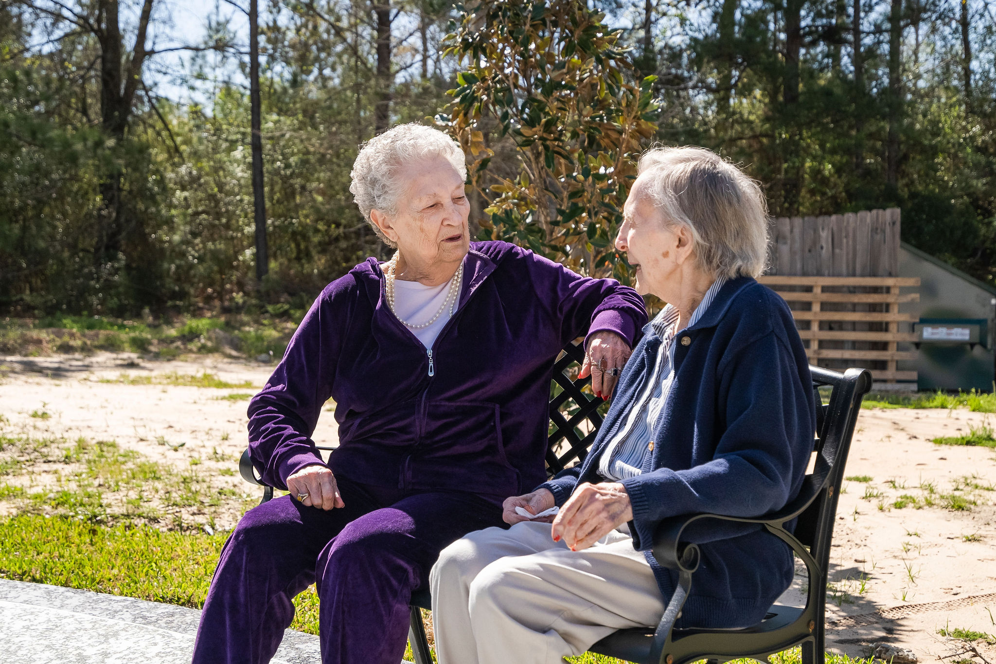 two older women laughing together on a bench